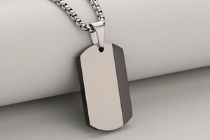 Macro view of silver and black stainless steel military tag pendant on a ball chain