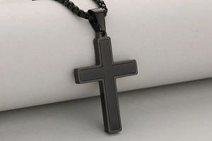 Detailed close-up of a two-tone black minimalist cross pendant with matte brushed texture