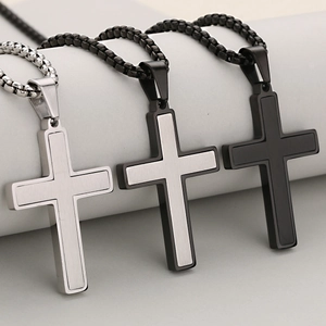 Minimalist stainless steel cross pendants in silver and black on a white podium