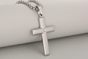 Macro shot of polished silver cross pendant with a centered zircon and link chain