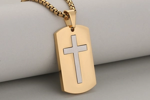 Detailed close-up of gold dog tag pendant with silver cross inlay and box chain