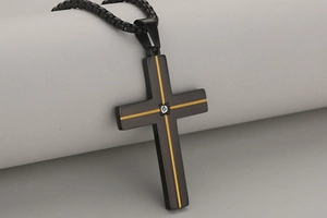 Detail van zwarte roestvrijstalen kruishanger met gouden lijnen en kleine diamant