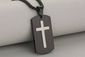 Macro close-up of matte black stainless steel dog tag necklace with silver cross detail
