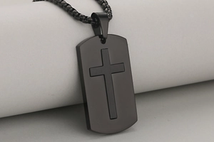 Close-up of matte black stainless steel military tag pendant with cross relief detailing