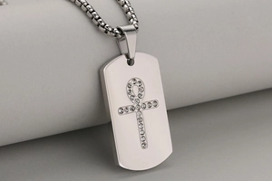 Macro detail of dog tag pendant with Ankh symbol and inlaid stones on stainless steel