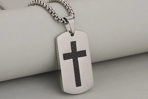Macro view of men's stainless steel dog tag pendant with black carbon fiber cross detail