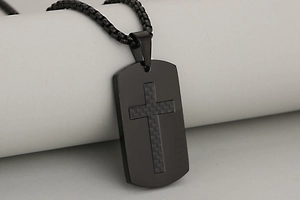 Macro shot of matte black stainless steel cross pendant with carbon fiber texture inlay