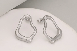 Detailansicht silberner unregelmäßiger Hohlohrringe mit polierter metallischer Textur