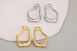 Makroaufnahme von unregelmäßigen organischen Ohrringen in Gold und Silber
