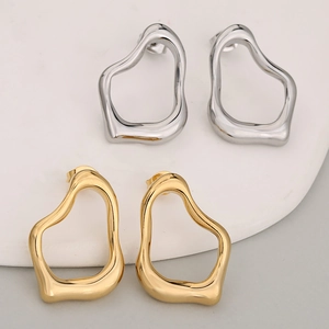 Minimalistische unregelmäßige hohle Ohrringe in Gold und Silber auf einem Tablett