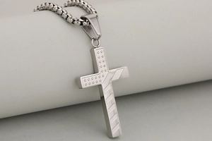 Detail of silver stainless steel cross pendant with stars and stripes industrial pattern