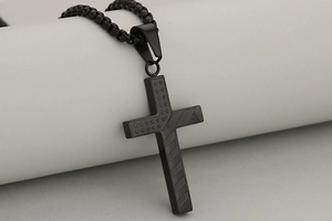 Detail of black stainless steel cross pendant with stars and stripes engraving on box chain