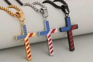 Detailed view of three stainless steel cross pendants with American flag patterns in gold, silver, and black