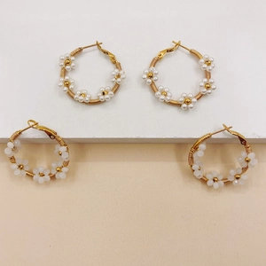 Detailed close-up of handmade beaded floral hoop earrings with white pearls and gold base