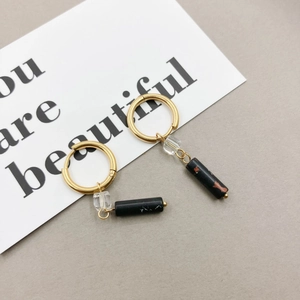 Ethnic style gold hoop earrings featuring a transparent bead and black stone cylinder pendant