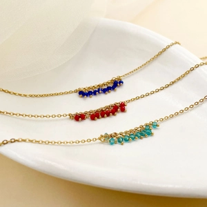 Détail de colliers plaqués or 14K avec grappes de perles de cristal bleu, rouge et vert