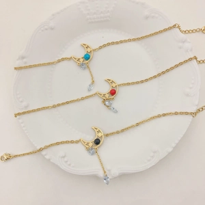 Bracelets lune dorés avec turquoise et strass présentés sur une assiette blanche