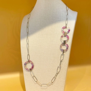 Détail du long collier en chaîne dorée avec anneaux en acrylique marbré violet sur buste