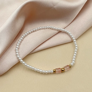 Détail du bracelet en perles d'eau douce et pierres roses sur tissu en soie champagne