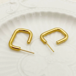 Vue macro détaillée de boucles d'oreilles géométriques en U dorées sur une assiette en céramique