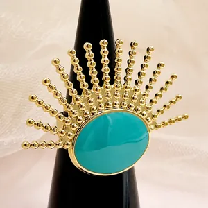 Detalle de anillo de sol dorado con centro ovalado turquesa en soporte negro