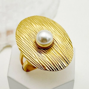 Vista macro de anillo ovalado dorado con textura radial y una perla central
