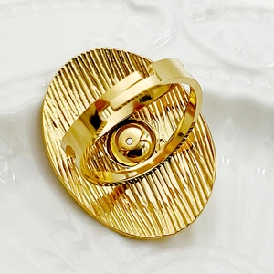 Primer plano de anillo ovalado dorado con textura radial y banda ajustable