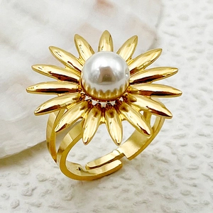 Vista macro de anillo de girasol dorado con perla blanca sobre fondo de piedra