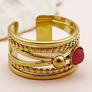Détail macro d'une bague multicouche plaquée or avec une gemme rouge et texture perlée