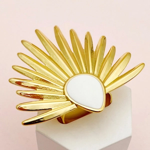 Detalle de un gran anillo dorado en forma de abanico con gota blanca sobre soporte decorativo