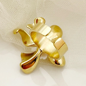 Détail d'une bague ouverte dorée aux motifs de pétales sur fond de tulle blanc doux