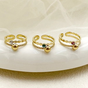 Détail de trois bagues dorées multicouches avec zircons colorés et petites perles en métal
