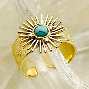 Détail d'une bague soleil vintage avec pierre turquoise et finition en or martelé