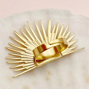 Detalle macro del anillo de sol dorado con banda abierta ajustable sobre mármol