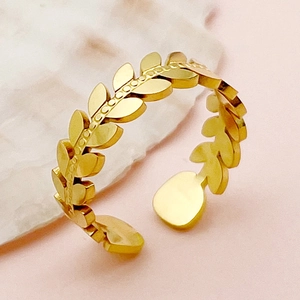 Vue détaillée d'une bague feuille de blé plaquée or réglable sur un socle en marbre