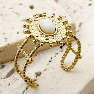 Détail d'une bague vintage soleil avec pierre blanche et anneau texturé doré