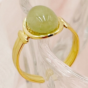Macroshot van een verstelbare goudkleurige ring met een ovale groene edelsteen en ribbeldetails