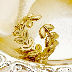 Détail d'une bague feuille d'olivier dorée avec textures fines sur fond de soie luxueux