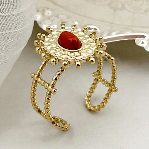 Détail de bague bohème dorée avec pierre rouge et finition martelée élégante