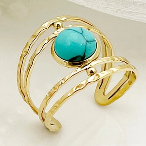 Vue macro d'une bague martelée dorée multicouche avec une pierre turquoise centrale