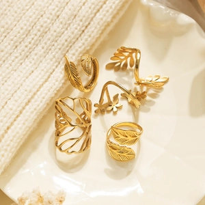 Detail van de 5-delige vintage gouden ringenset met blad en veer op keramieken schaal