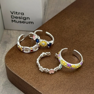 Nahaufnahme von drei Vintage-Emaille-Blumenringen auf rustikalem Holzgrund mit Dekoration