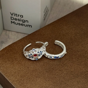 Detail eines silbernen Vintage-Rings mit blauen Emaille-Blättern und rotem Schmuckstein