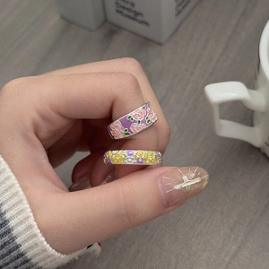 Detail von farbenfrohen Emaille-Ringen mit lila und rosa Blumenmustern auf Metall