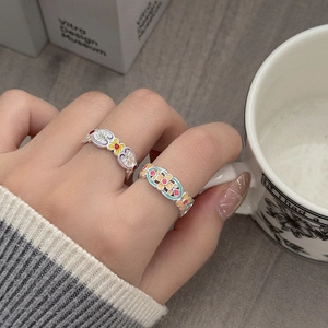 Nahaufnahme von Boho-Ringen mit bunten Emaille-Blumenmustern am Finger getragen
