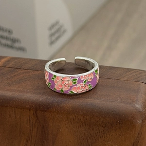 Detail eines Emaille-Blumenrings mit rosa Rosen auf dunkler Holzoberfläche