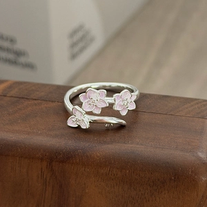 Nahaufnahme von rosa Emaille-Kirschblüten und kleinen Diamanten auf einem silbernen Ring