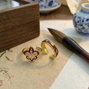 Close-up of vintage red enamel iris rings with sparkling crystals on a wooden set