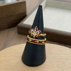 Vintage gold fleur-de-lis ring set with red enamel and diamonds on a display stand