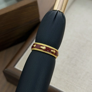 Macro shot of vintage gold-plated ring with burgundy enamel and fine milgrain textures
